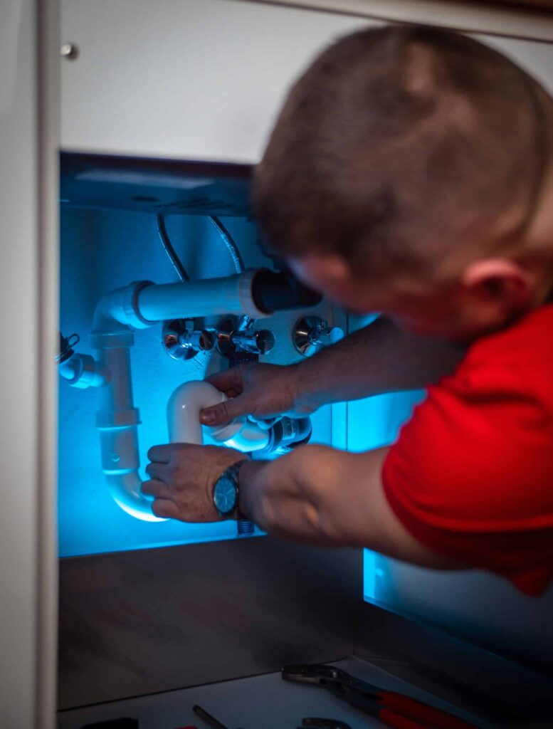 Plumber repairing under-sink plumbing in Denver, PA