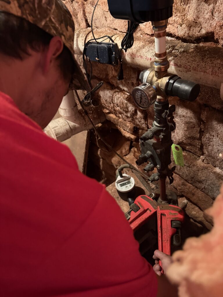 Technician servicing well pump and pressure tank piping